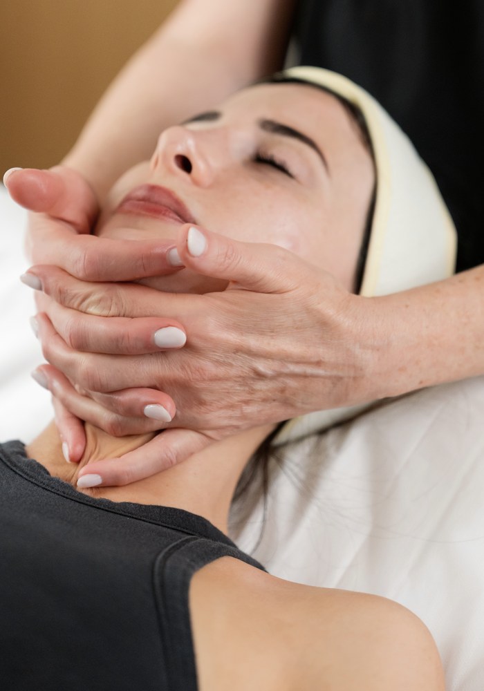 Sophie cradling a client’s jaw during a facial